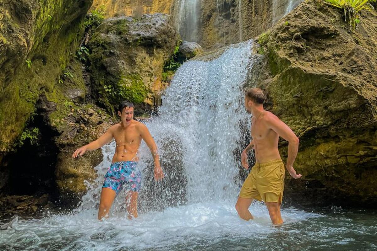 dua lelaki berdiri di dalam air di hadapan air terjun