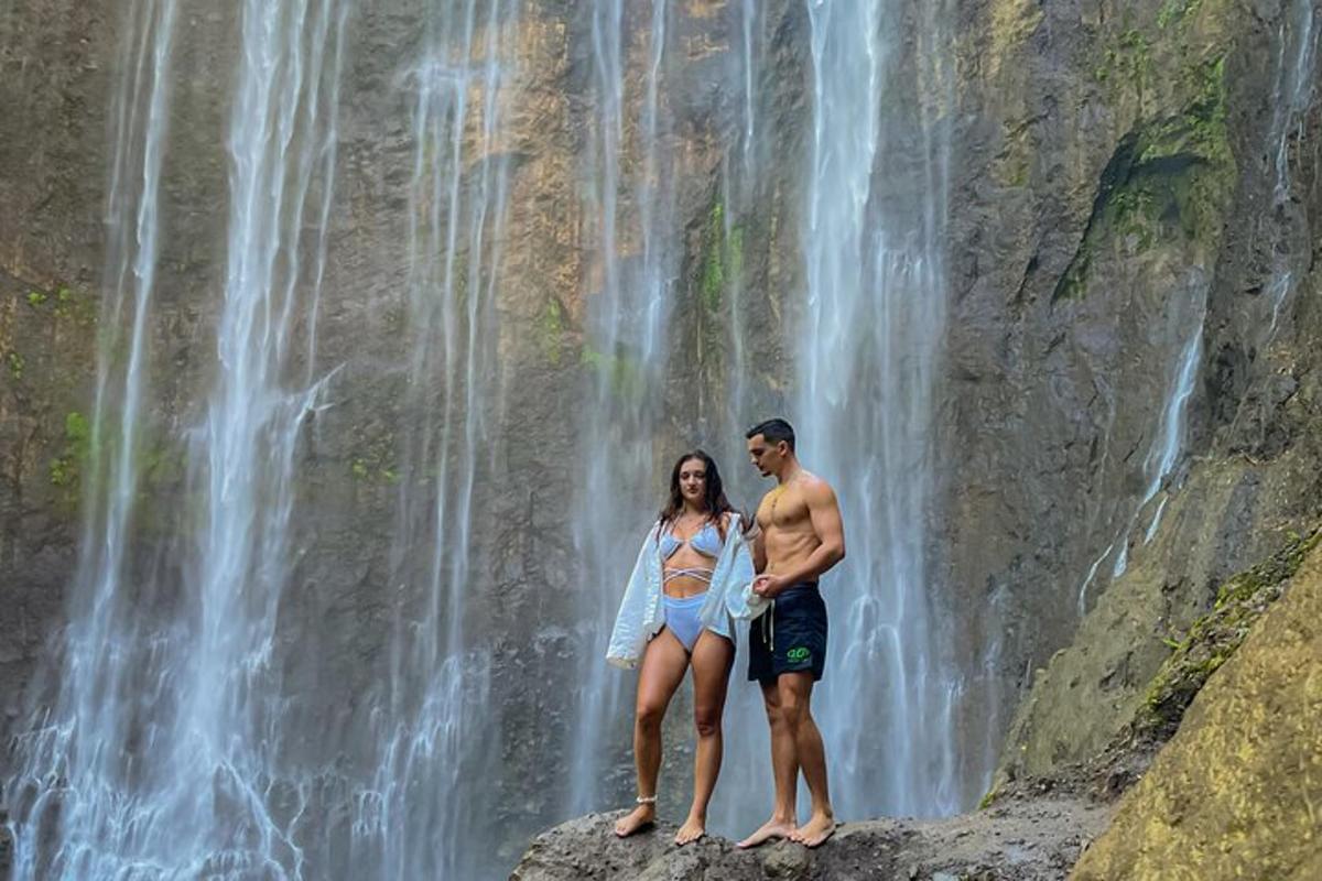 ein Mann und eine Frau stehen vor einem Wasserfall