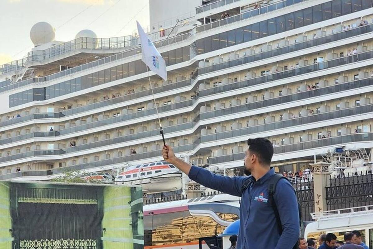 un bărbat care ține un steag în fața unui vas de croazieră