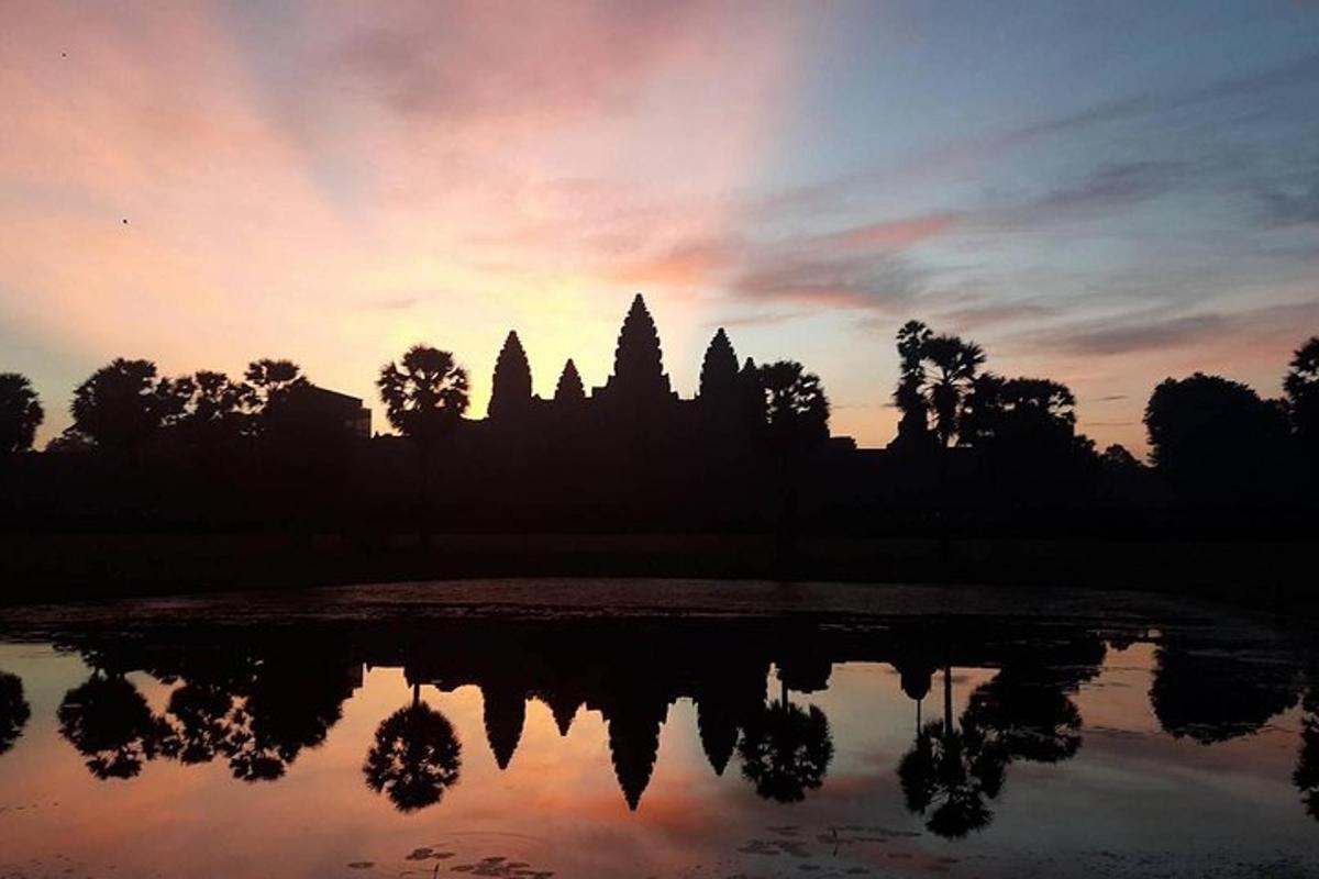 a silhouette of a temple at sunset with a reflection in the water
