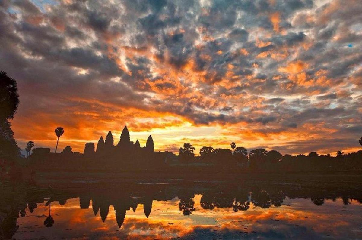 um pôr do sol com o reflexo de um templo na água