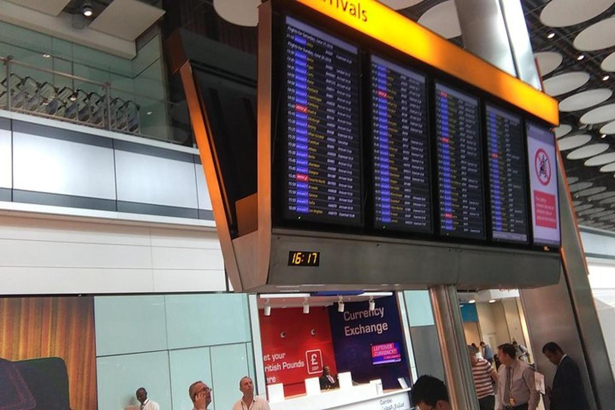 a departure board in an airport with people walking around