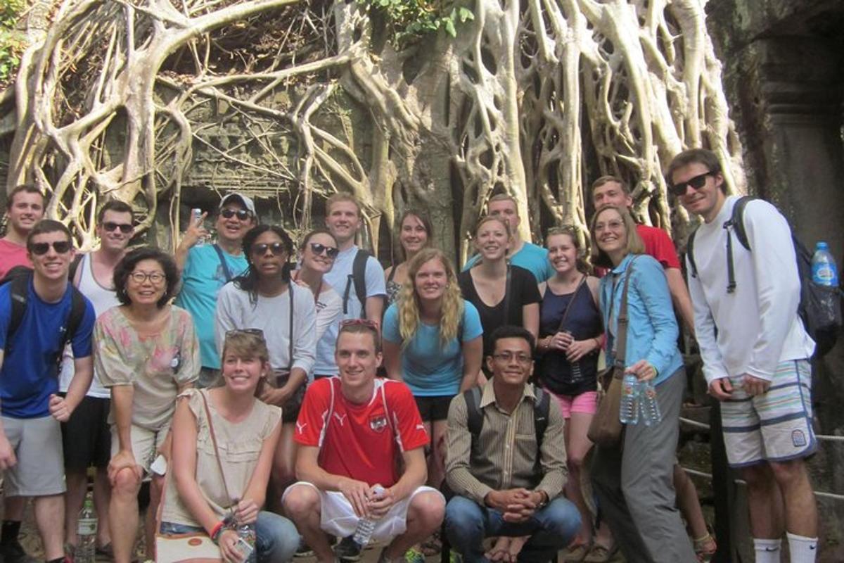 a group of people posing in front of a tree