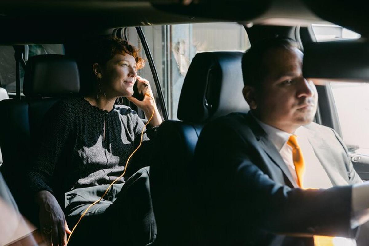 um homem e uma mulher sentados em um carro conversando ao celular
