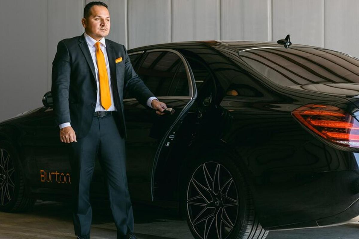 Ein Mann in Anzug und Krawatte steht neben einem Auto