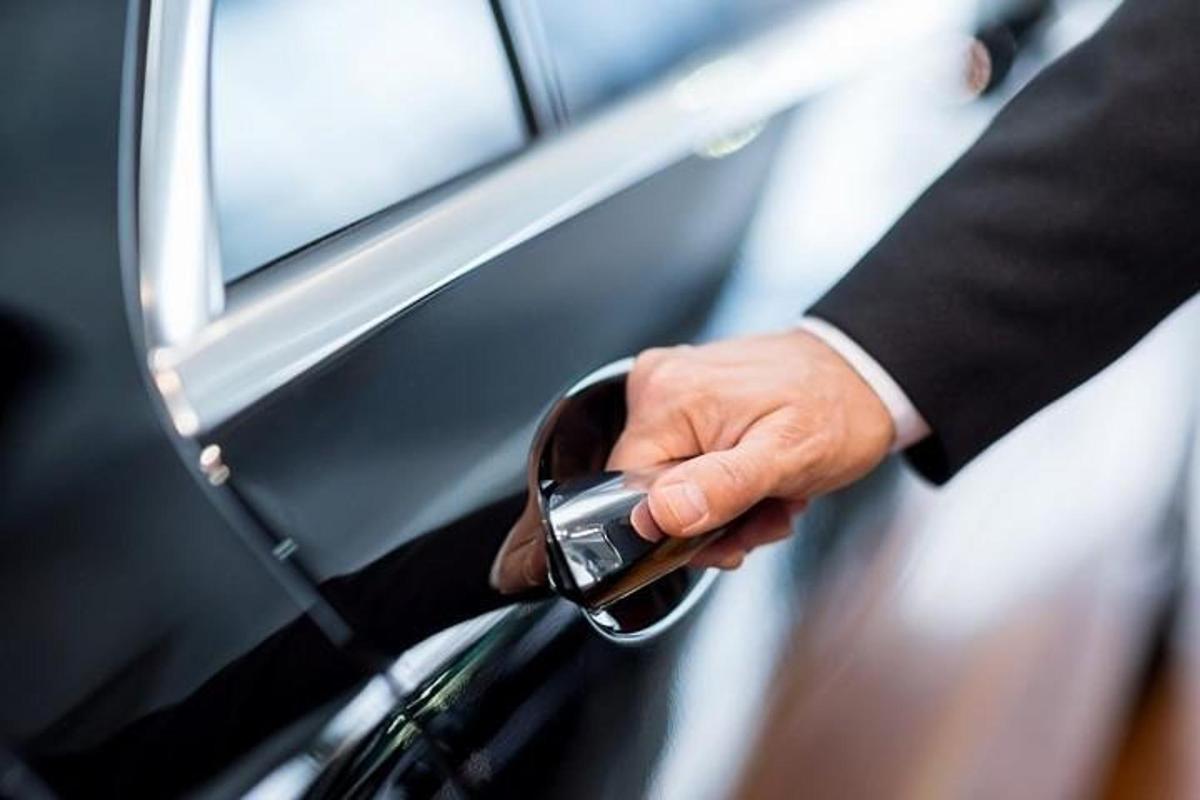 un uomo in giacca e cravatta che tiene in mano un apriporta per auto