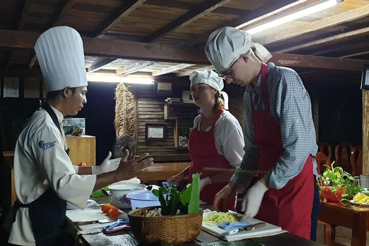 tres persones amb barrets de xef preparant menjar a la cuina