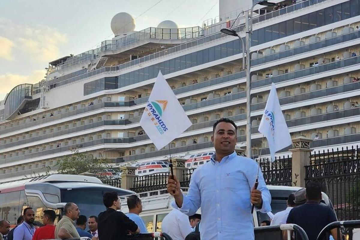 un uomo che tiene bandiere davanti a una nave da crociera