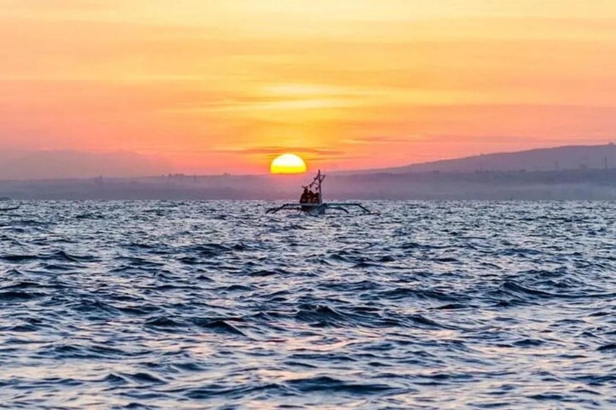 a boat in the ocean with a sunset