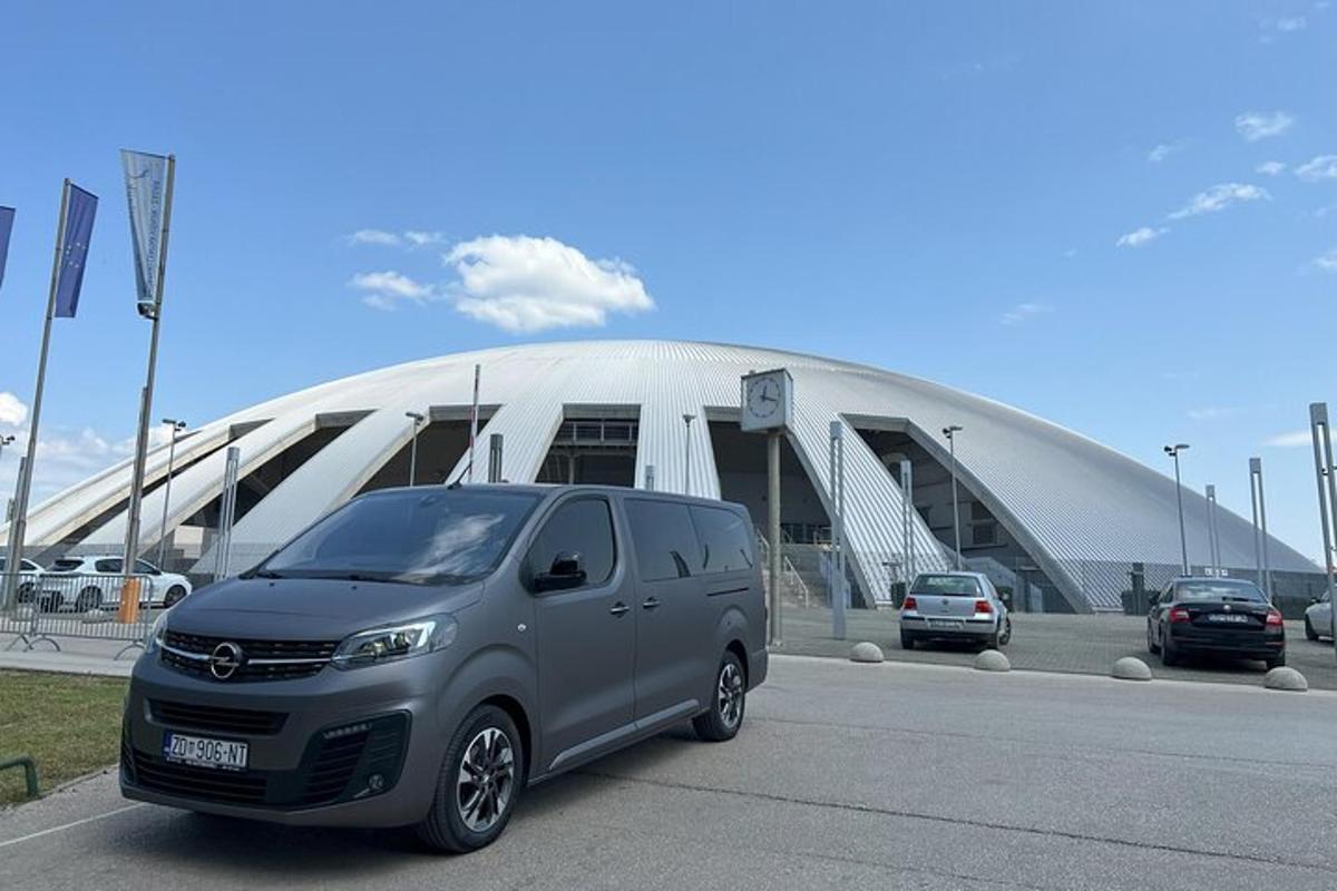 hopeinen pakettiauto pysäköitynä suuren rakennuksen eteen
