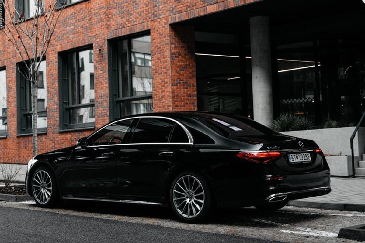 um carro preto estacionado em frente a um prédio de tijolos