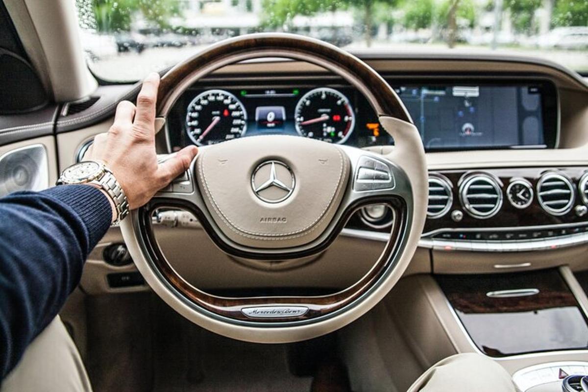 um homem dirigindo um carro com a mão no volante