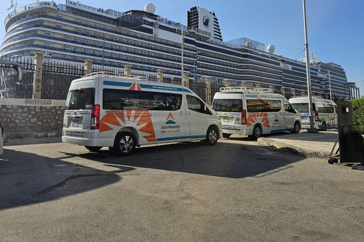 três vans estacionadas em um estacionamento em frente a um navio de cruzeiro