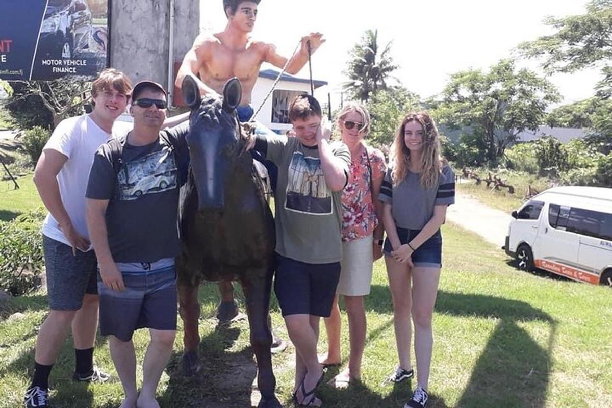 a group of people standing next to a statue of a man on a horse