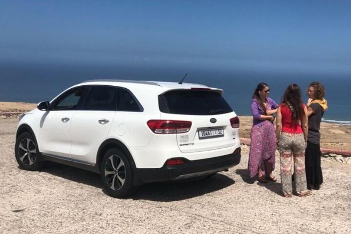 a group of women standing next to a white car