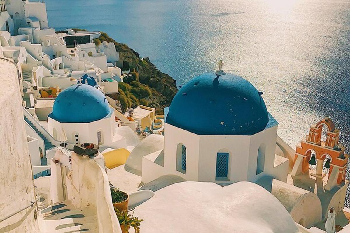 un gruppo di edifici bianchi con cupole blu e l'oceano