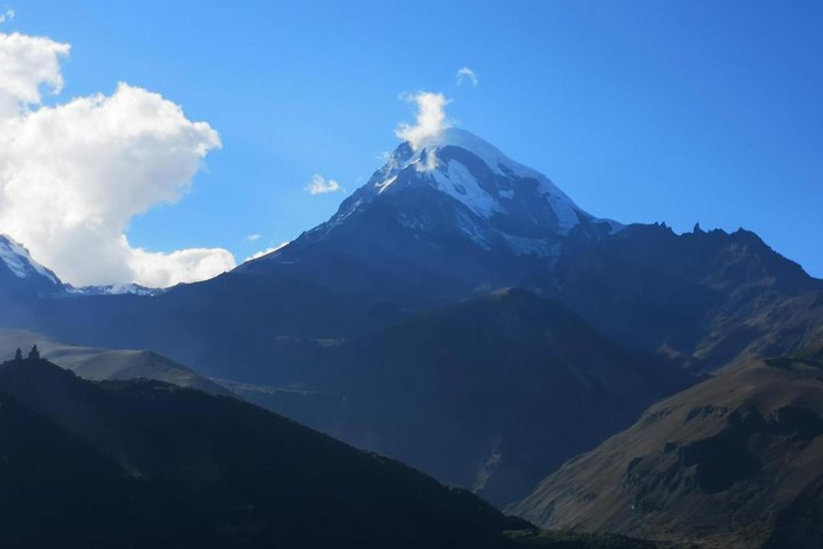 a view of a mountain with a blue sky and clouds