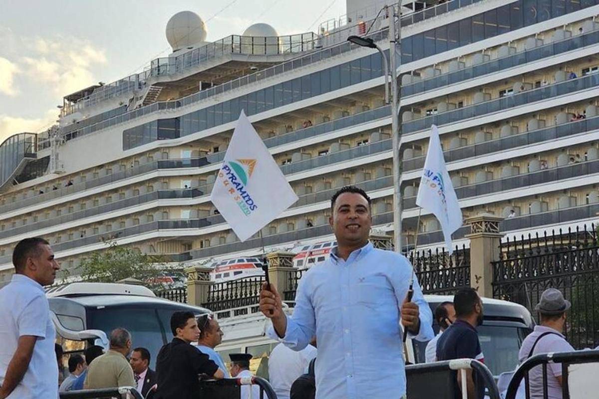 Un hombre sosteniendo banderas frente a un crucero.