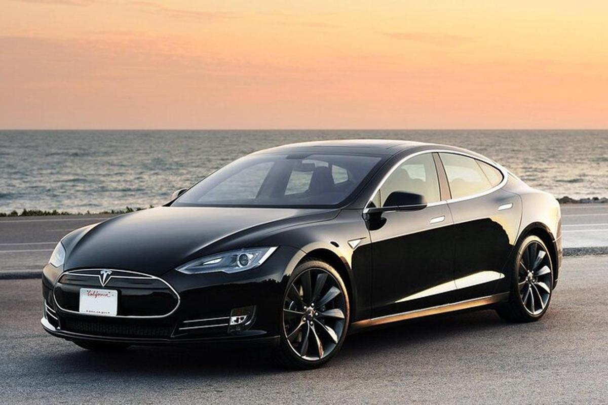 a black and white car parked next to the ocean