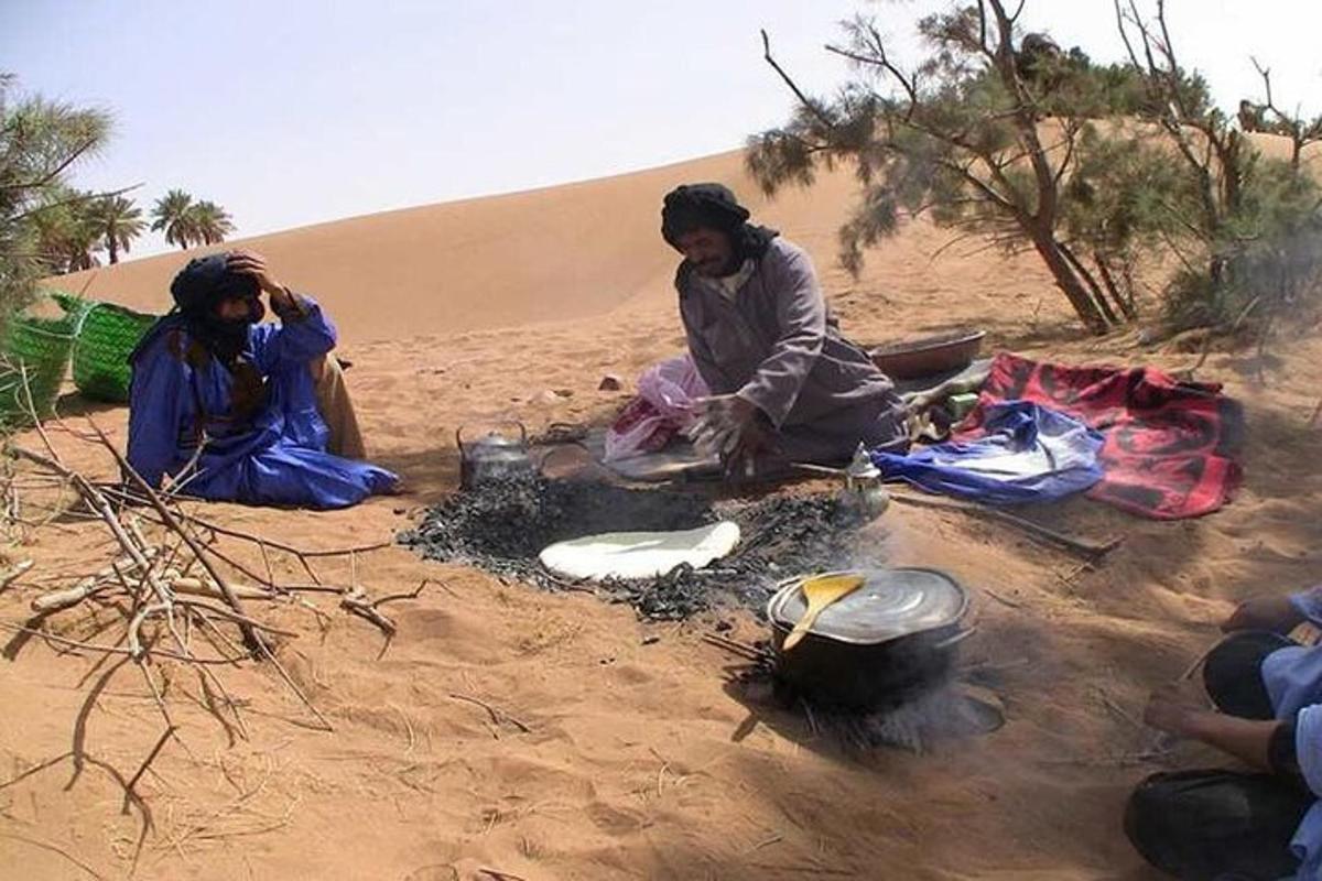 two women sitting in the sand in the desert