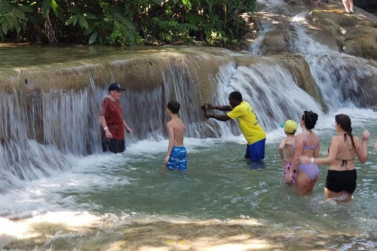 een groep mensen die in het water staan bij een waterval
