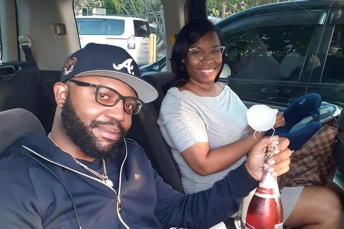 Un hombre y una mujer sentados en un coche sosteniendo una botella.