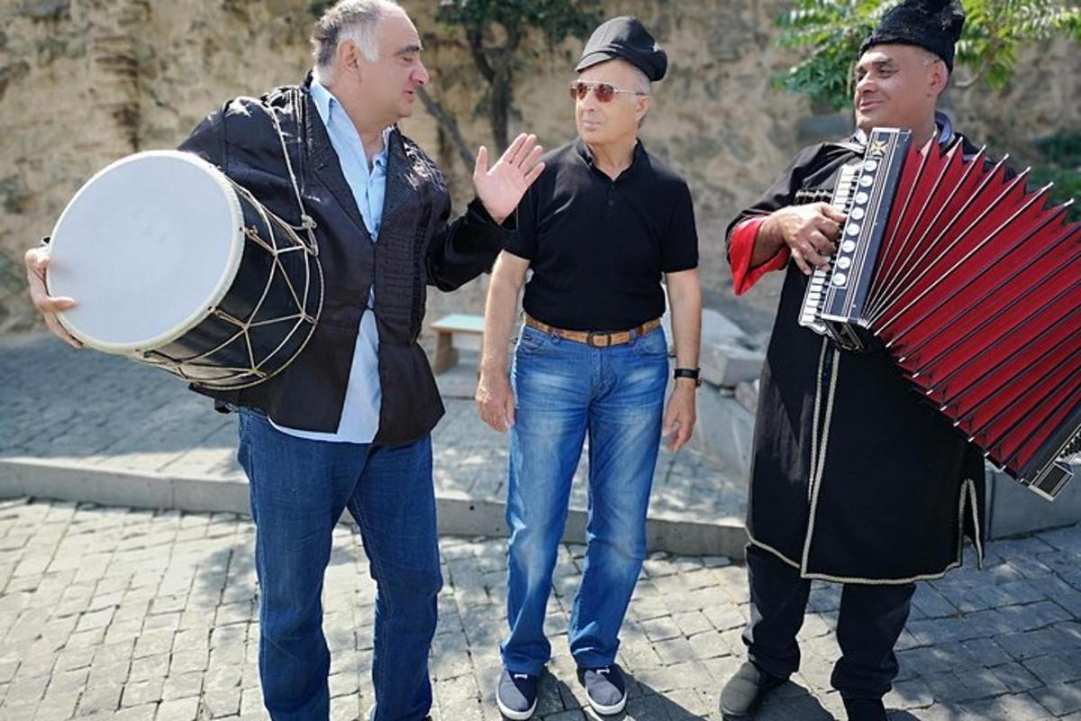 Un grupo de tres hombres de pie en una calle con un acordeón.