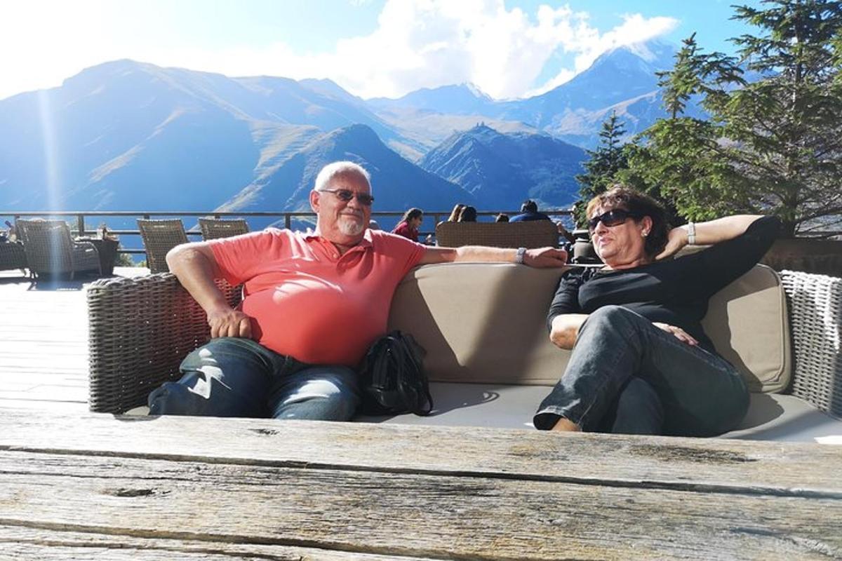 due uomini seduti su una panchina con le montagne sullo sfondo