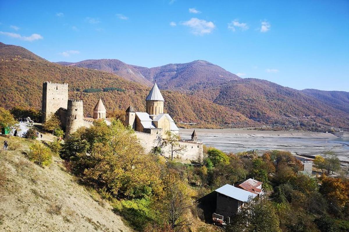 un castillo en la cima de una colina junto a un río
