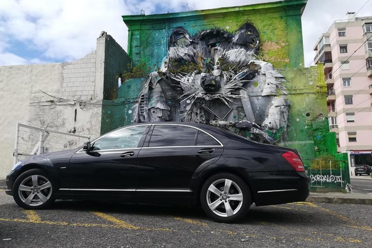 ein schwarzes Auto, das auf einem Parkplatz vor einem Wandgemälde geparkt ist