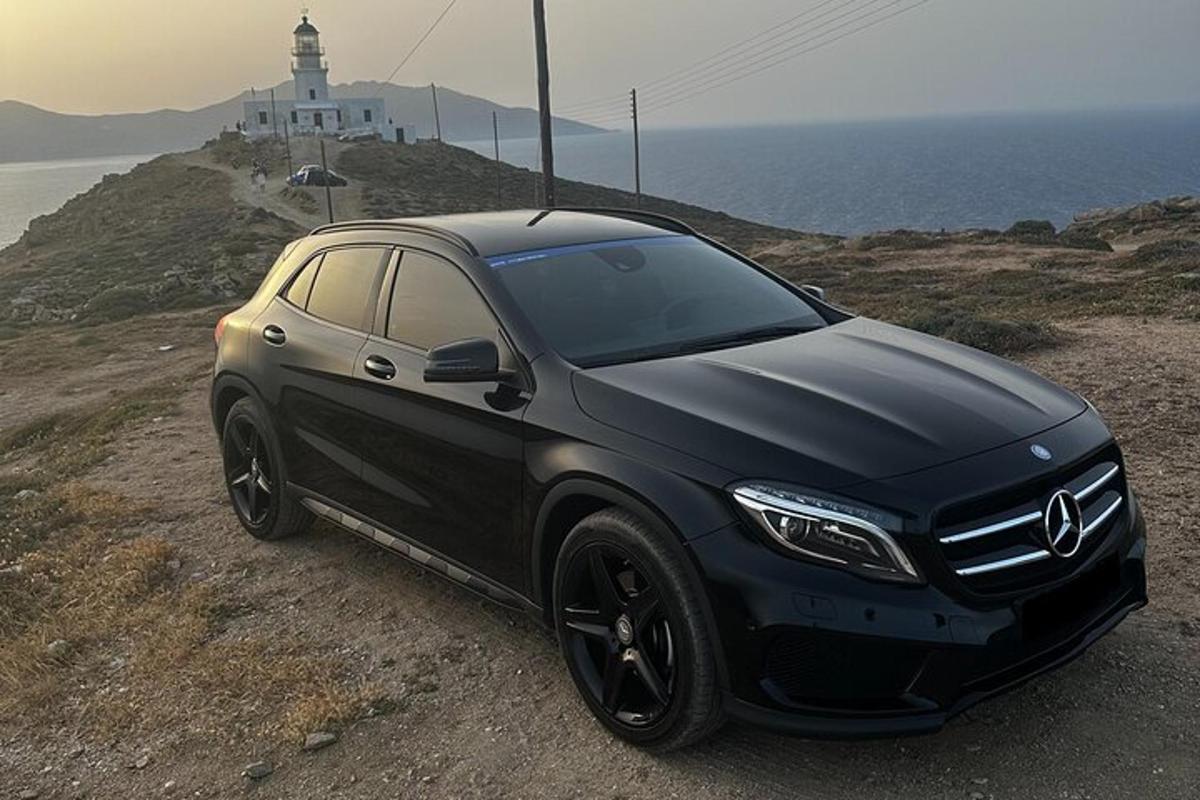 um carro preto estacionado na encosta de uma colina com um farol