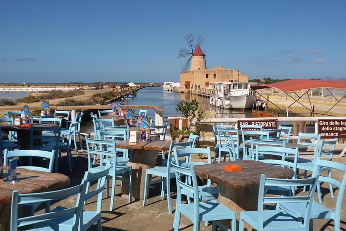 a row of tables and chairs with a windmill in the background