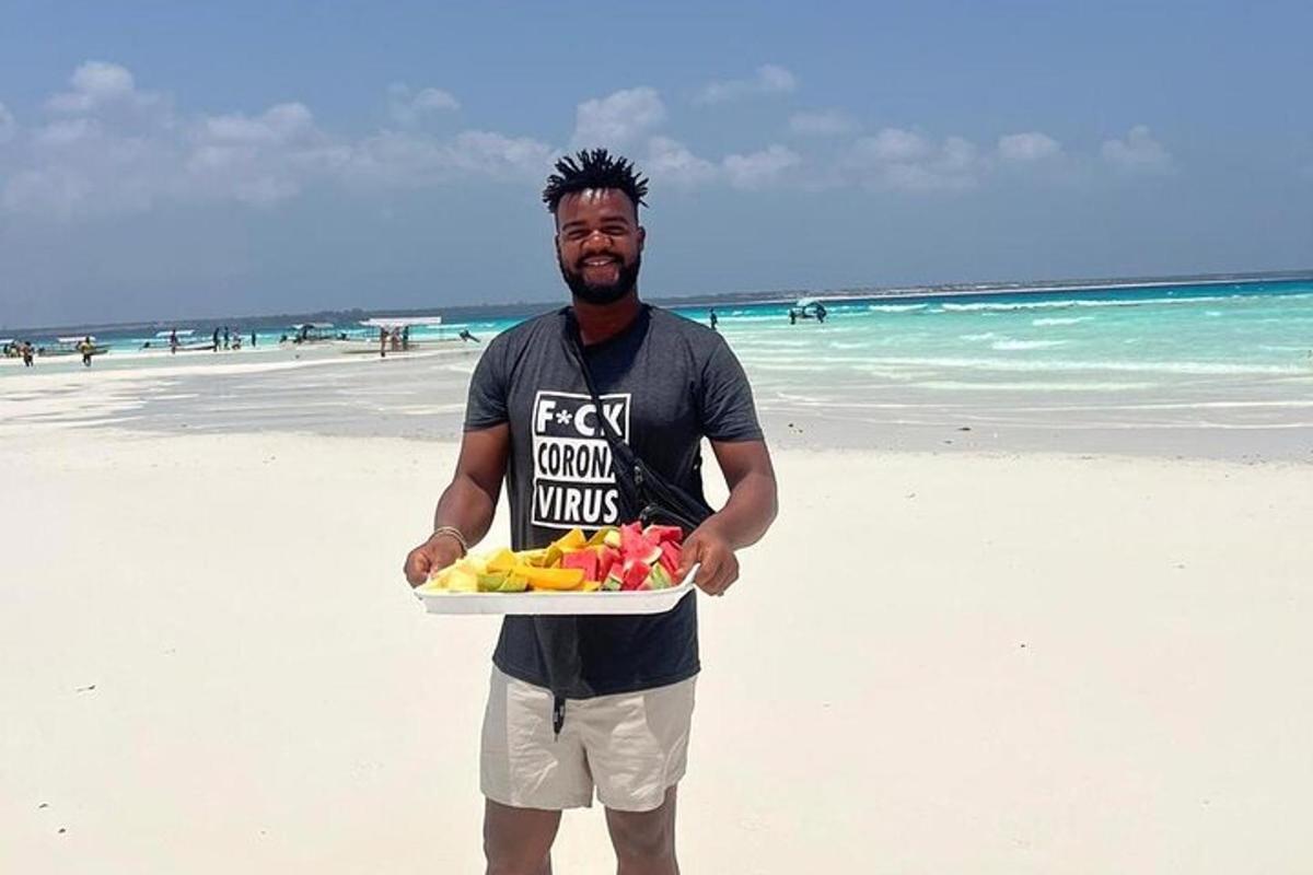 um homem segurando uma bandeja de frutas na praia