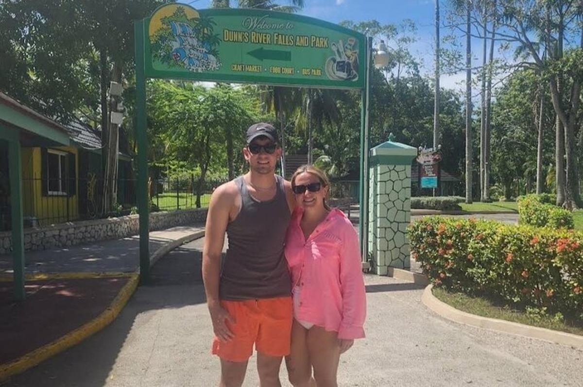 Un hombre y una mujer de pie frente a un cartel