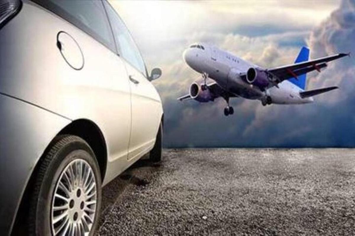 um carro estacionado ao lado de um avião voando no céu