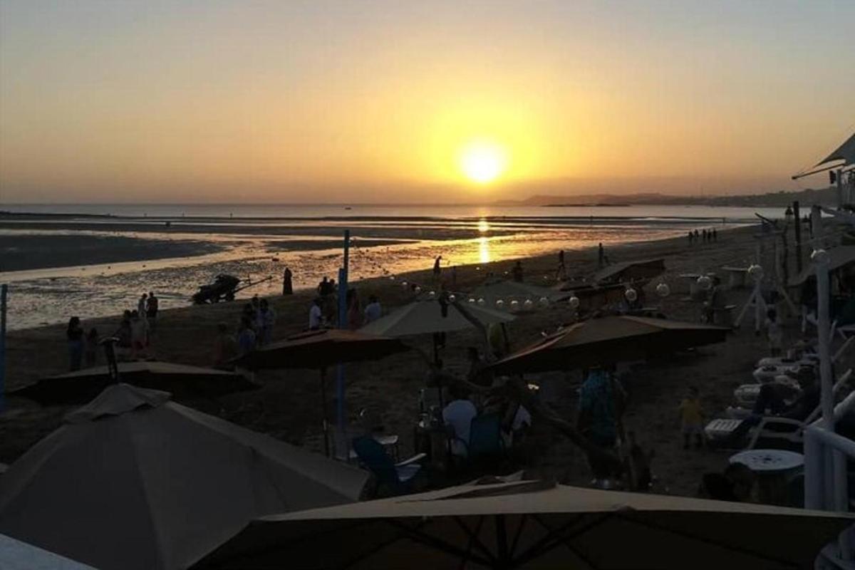 egy strand napernyőkkel és emberekkel a parton naplementekor