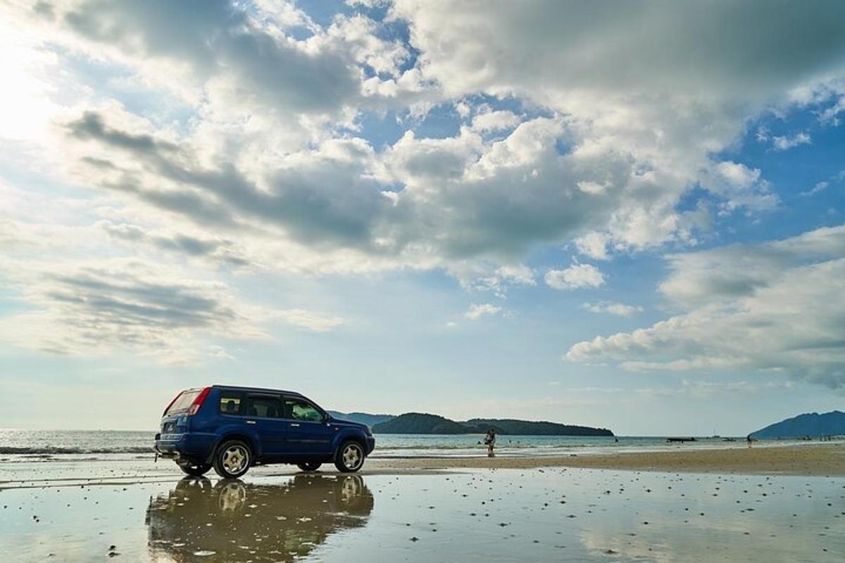 a blue car parked on a beach near the ocean