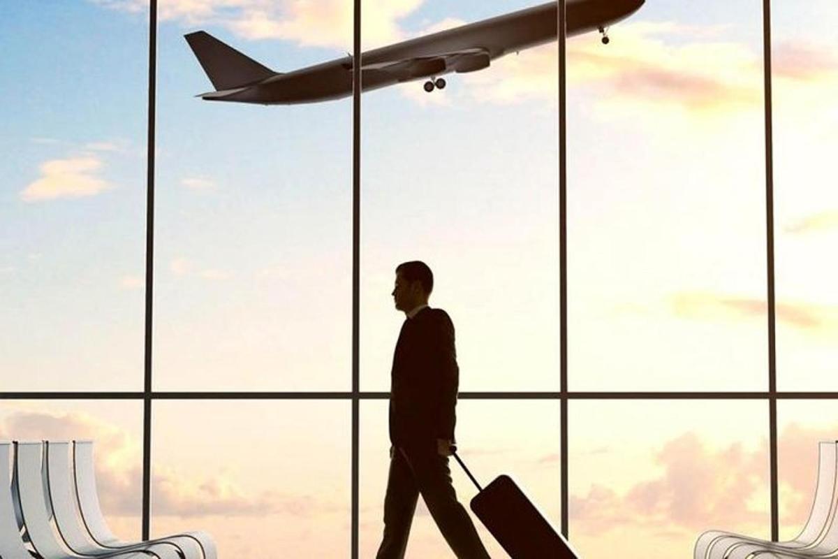 un home caminant davant d'una finestra d'aeroport amb un avió
