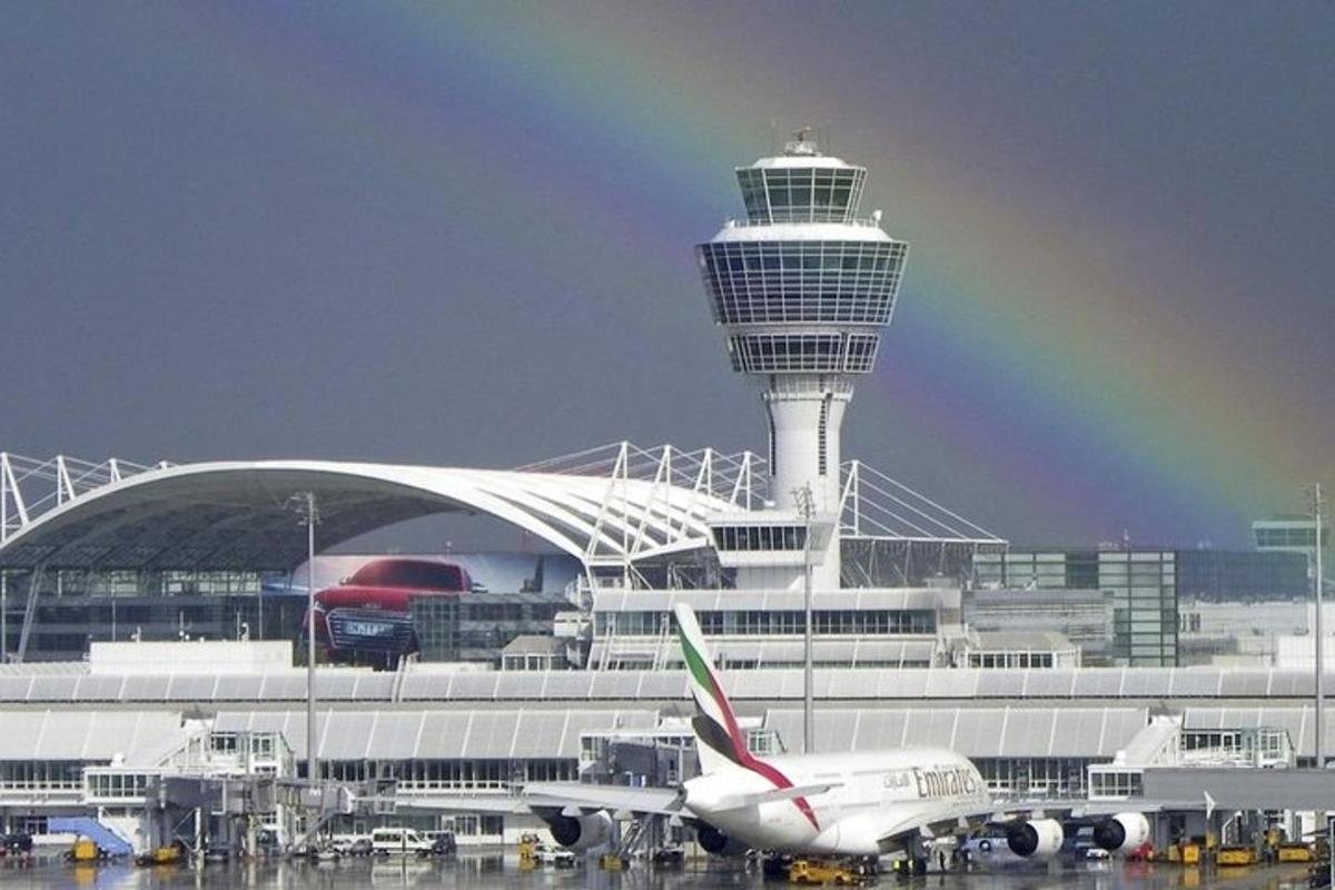 un avió aparcat a un aeroport amb un arc de Sant Martí al cel