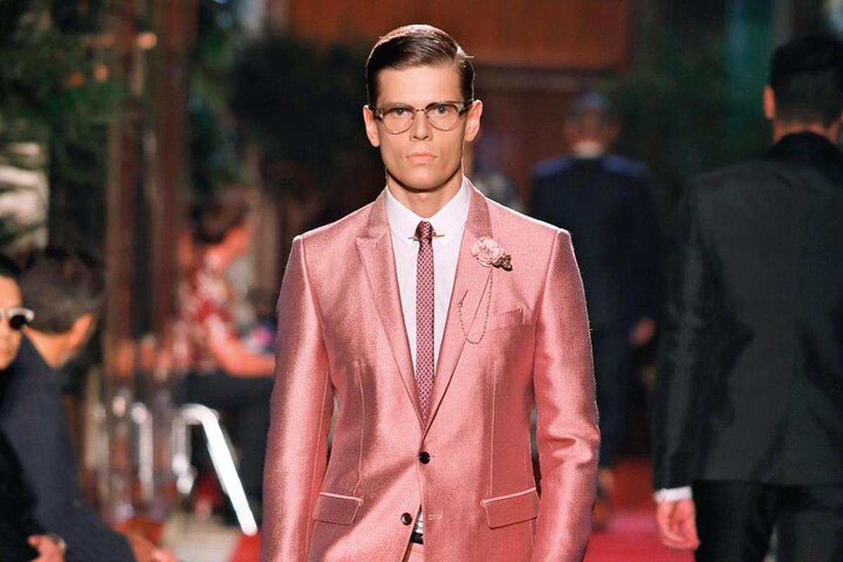 a man walking down the street wearing a pink suit and tie