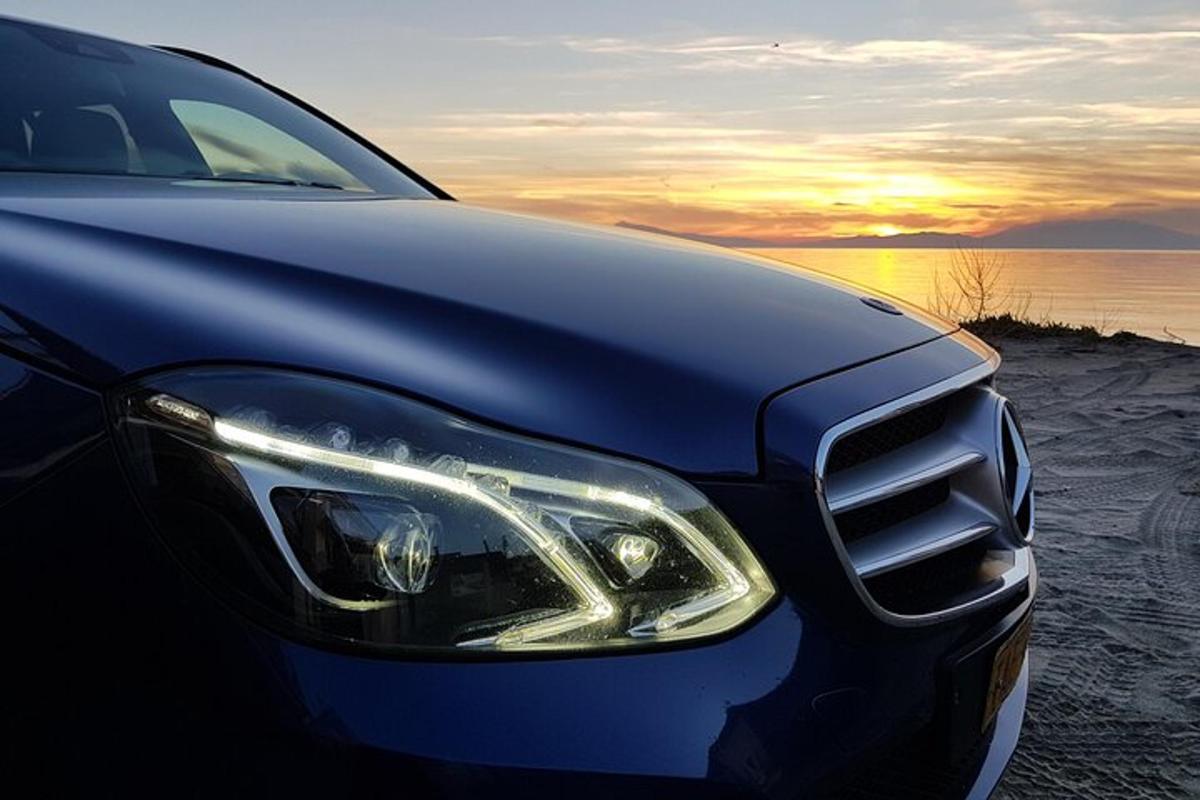 un'auto nera parcheggiata sulla spiaggia al tramonto