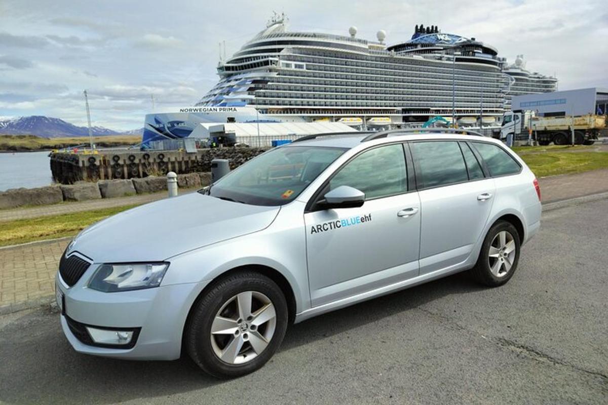a white car parked in front of a cruise ship
