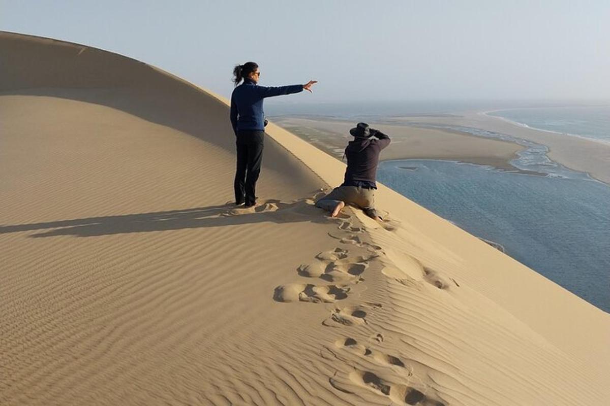 two people standing on top of a sand dune