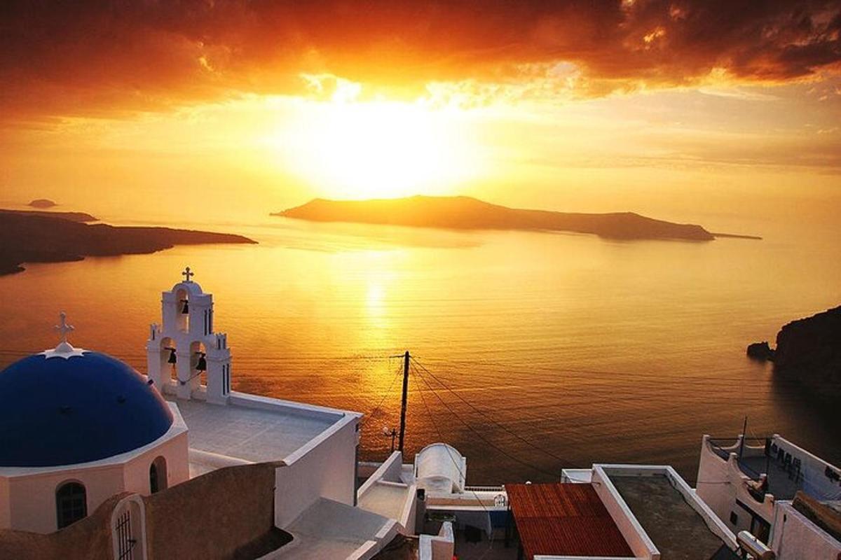 um pôr do sol sobre o oceano com uma igreja e um edifício