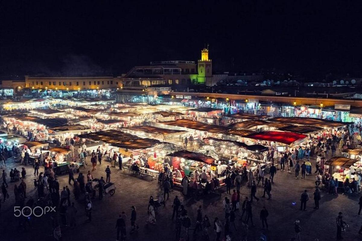 a crowd of people walking around a market at night