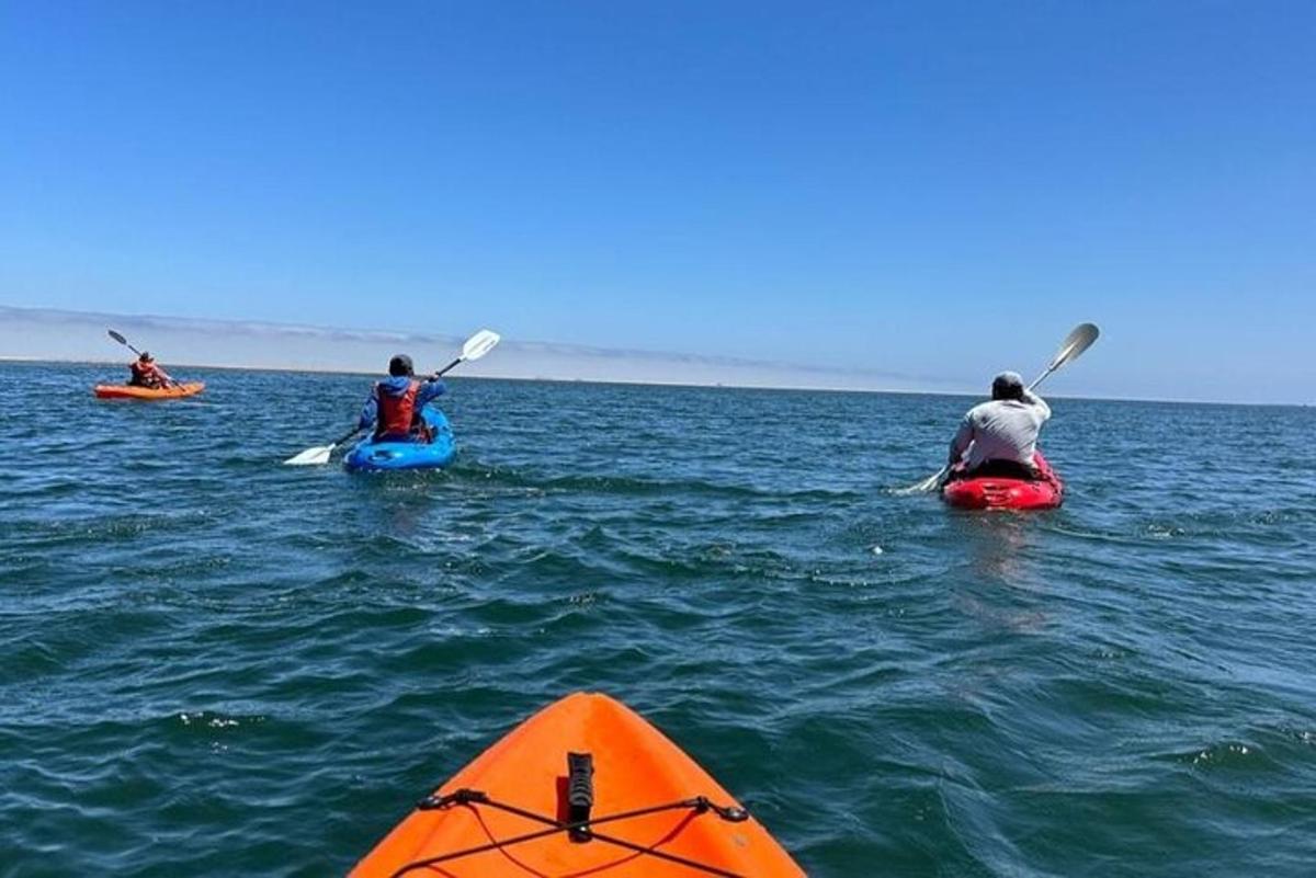 three people are kayaking in the ocean on the water