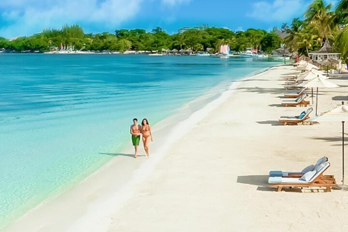 two people walking on a beach in the water