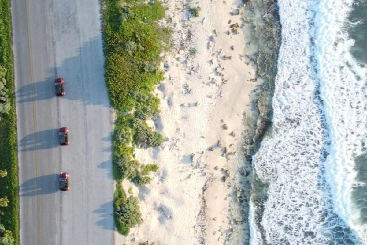 dos cotxes circulant per una carretera al costat de la platja