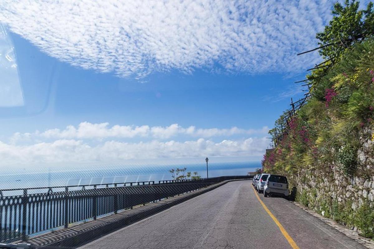 uma estrada com carros estacionados ao lado do oceano