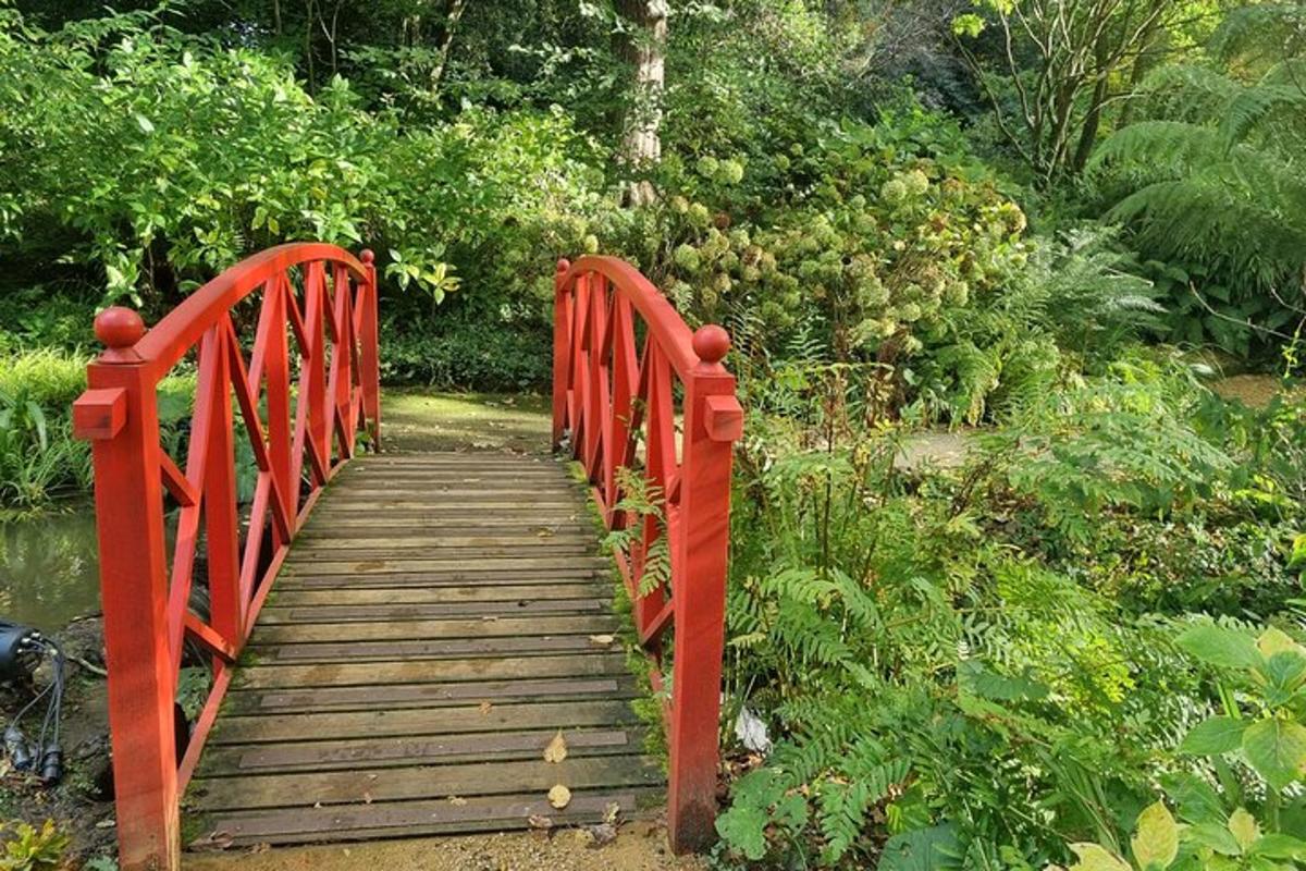 a red bridge with a wooden walkway in a garden
